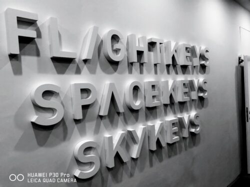 Weiß gestrichene Styrodur-Buchstaben, an einer weißen Wand montiert.