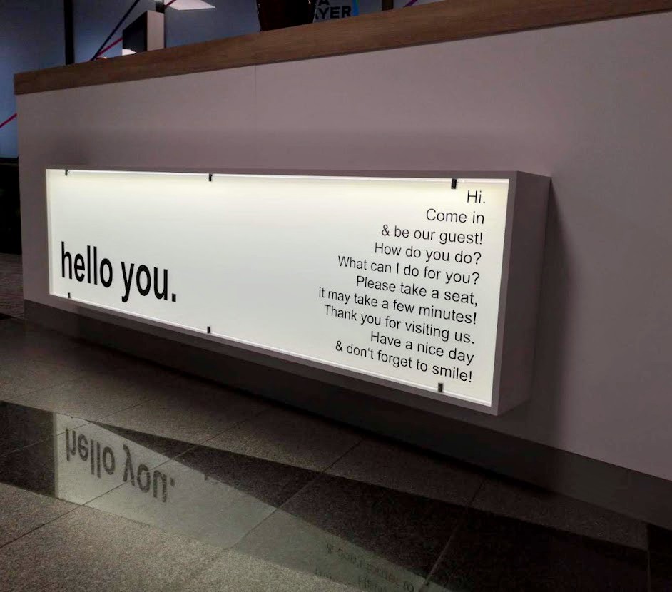 Ein langer, rechteckiger Leuchtkasten mit schwarzem Text auf weißem Hintergrund.